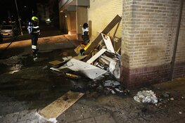 Brandweer blust stapel grofvuil tegen muur van flat