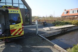 Vrouw rijdt met motor via sloot voortuin binnen