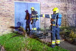 Stapel kerstbomen in brand tegen sporthal in Broekpolder