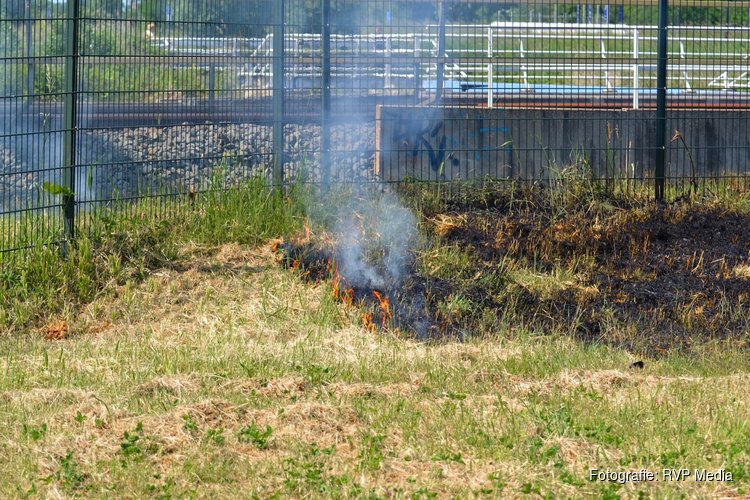 Brandweer blust brandend gras naast spoor Beverwijk