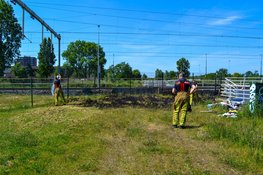Brandweer blust brandend gras naast spoor Beverwijk